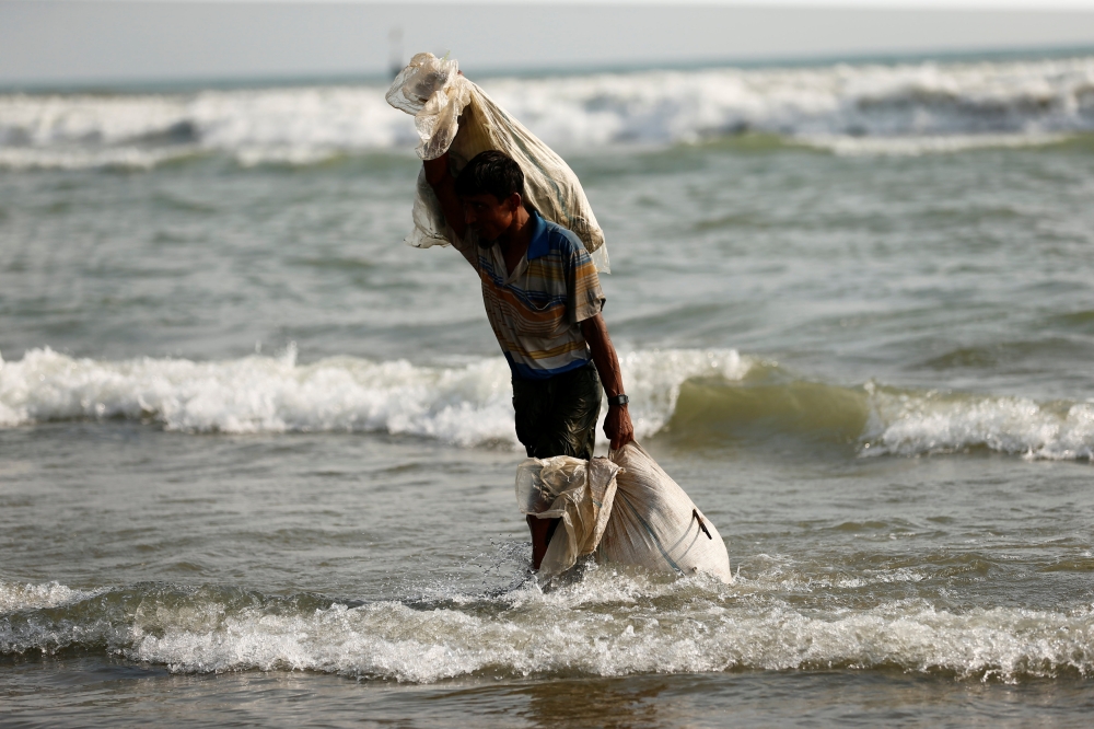 A Rohingya refugee walks to the shore with his belongings after crossing the Bangladesh-Myanmar border by boat through the Bay of Bengal in Teknaf, Bangladesh, September 5, 2017. REUTERS/Mohammad Ponir Hossain