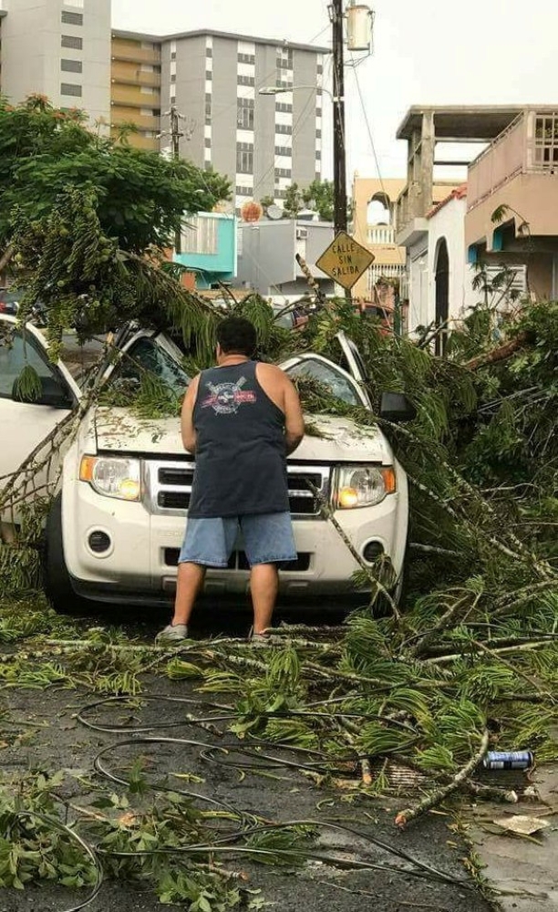 A man removes debris from a car following high winds as Hurricane Irma nears San Juan, Puerto Rico September 6, 2017, in this image taken from social media.  Mandatory credit NICOLE PELLOT/Handout via REUTERS   ATTENTION EDITORS - THIS IMAGE HAS BEEN SUPPLIED BY A THIRD PARTY. NO RESALES. NO ARCHIVE. REUTERS IS UNABLE TO INDEPENDENTLY VERIFY THE AUTHENTICITY, CONTENT, LOCATION OR DATE OF THIS IMAGE.