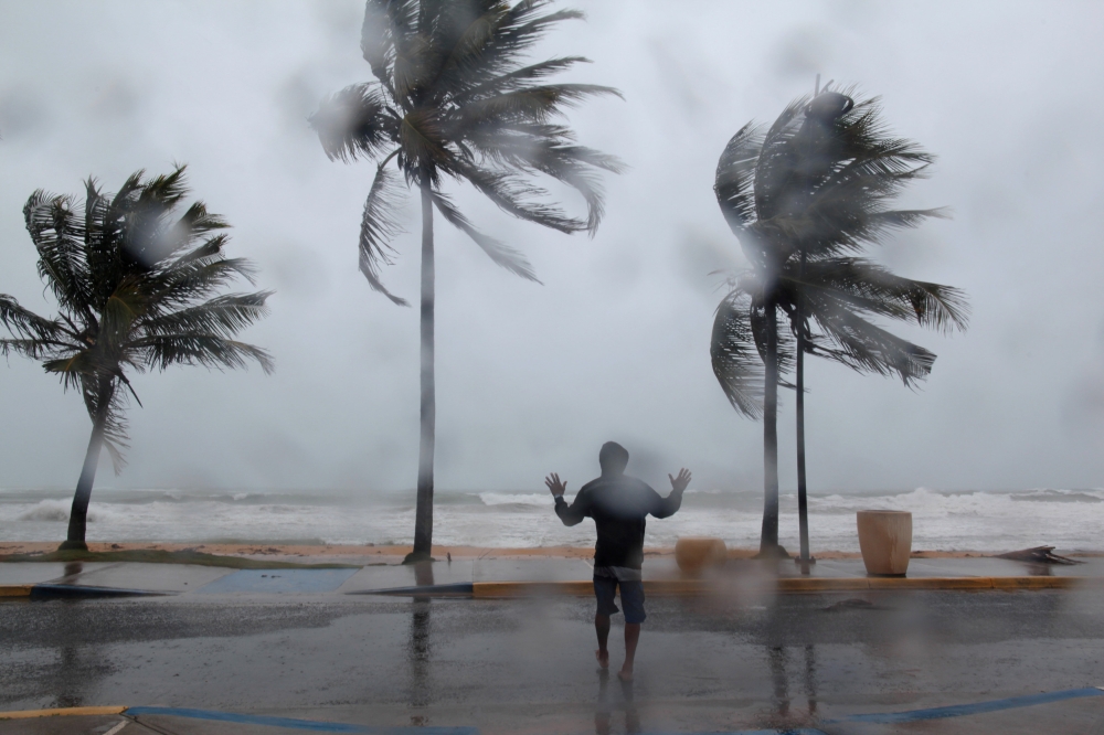 A man reacts in the winds and rain as Hurricane Irma slammed across islands in the northern Caribbean on Wednesday, in Luquillo, Puerto Rico September 6, 2017.  REUTERS/Alvin Baez