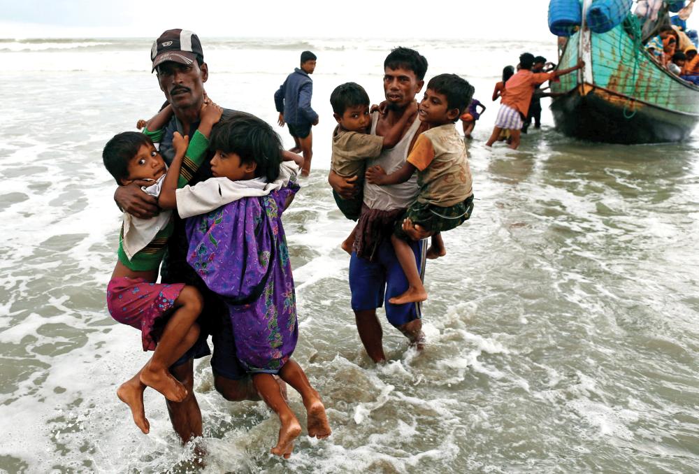 لاجئان ينقلان أولادهما من قارب أمس. (رويترز)