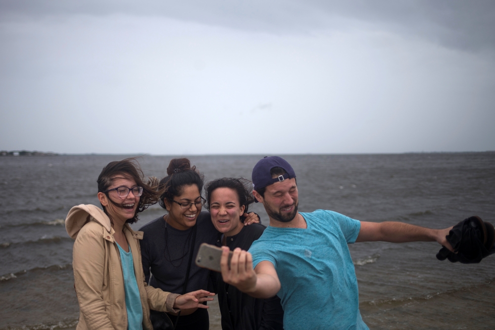 Friends (L-R) Estefania Garcia, Priya Shah, Valeria Yepes and Joshua Murphy attempt to take a selfie after walking into Hillsborough Bay ahead of Hurricane Irma in Tampa, Florida, U.S. September 10, 2017.  REUTERS/Adrees Latif
