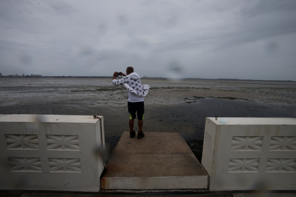 A man photographs Hillsborough Bay after water receded from the harbour ahead of the arrival of Hurricane Irma in Tampa, Florida, U.S., September 10, 2017. REUTERS/Chris Wattie