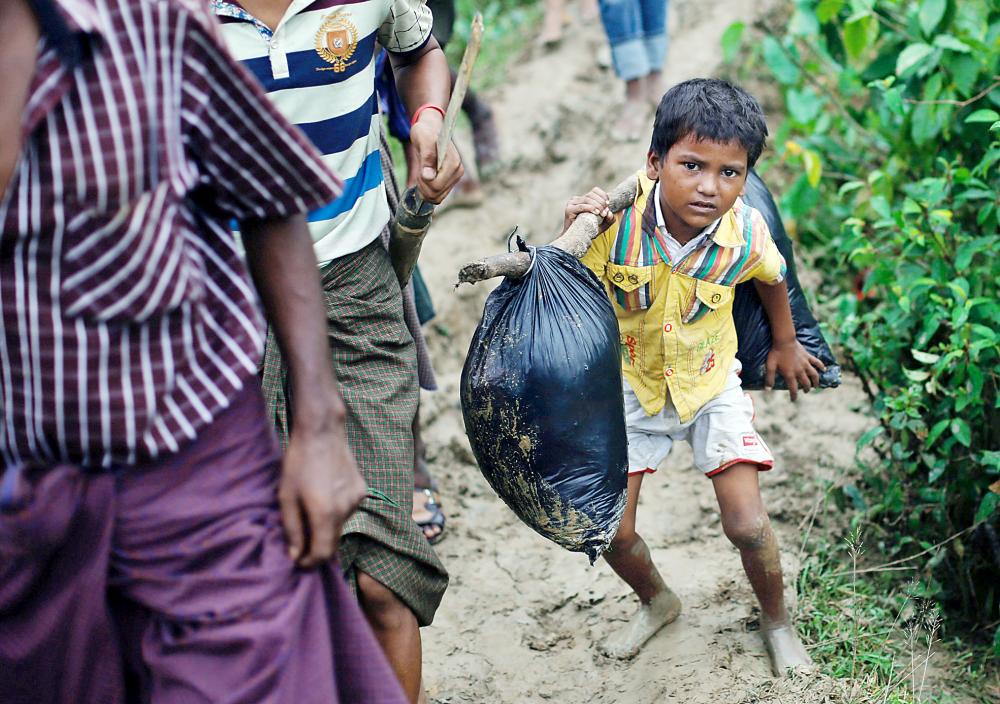 



روهينغيون فارون من التطهير العرقي في بورما في طريقهم إلى مخيمات اللجوء في بنغلاديش أمس. (رويترز)
