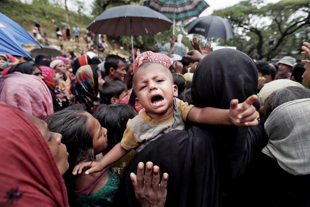 رضيع يصرخ على كتف أمه خلال زحام على المساعدات في بنجلاديش أمس.(رويترز)