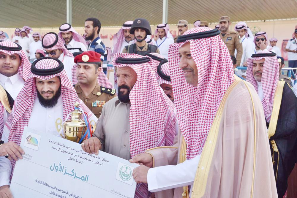 أمير الباحة الأمير حسام بن سعود يسلم الفائز بالمركز الأول في سباق الفروسية على كأس سموه، ويبدو محافظ العقيق غلاب أبو خشيم.