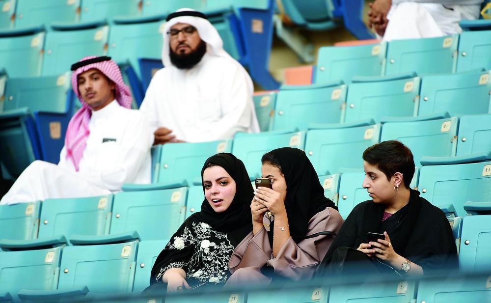Saudi families sit in a stadium to attend an event in the capital Riyadh on September 23, 2017 commemorating the anniversary of the founding of the kingdom. The national day celebration coincides with a crucial time for Saudi Arabia, which is in a battle for regional influence with arch-rival Iran, bogged down in a controversial military intervention in neighbouring Yemen and at loggerheads with fellow US Gulf ally Qatar. / AFP / Fayez Nureldine
