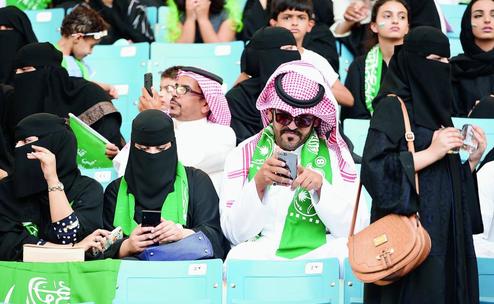Saudi families sit in a stadium to attend an event in the capital Riyadh on September 23, 2017 commemorating the anniversary of the founding of the kingdom. The national day celebration coincides with a crucial time for Saudi Arabia, which is in a battle for regional influence with arch-rival Iran, bogged down in a controversial military intervention in neighbouring Yemen and at loggerheads with fellow US Gulf ally Qatar. / AFP / Fayez Nureldine
