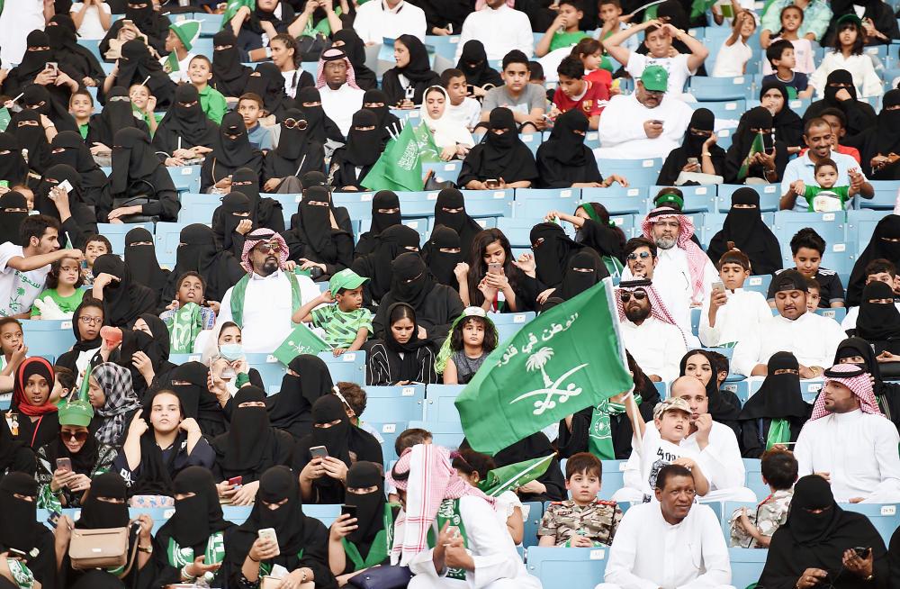 Saudi families sit in a stadium waving national flags, to attend an event in the capital Riyadh on September 23, 2017 commemorating the anniversary of the founding of the kingdom. The national day celebration coincides with a crucial time for Saudi Arabia, which is in a battle for regional influence with arch-rival Iran, bogged down in a controversial military intervention in neighbouring Yemen and at loggerheads with fellow US Gulf ally Qatar. / AFP / Fayez Nureldine
