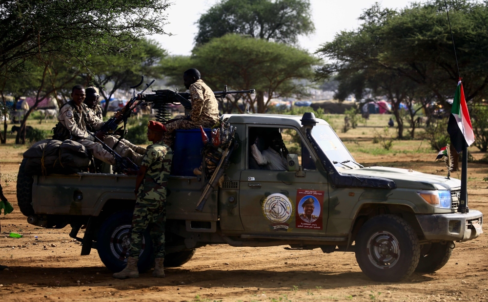 Sudanese members of the Rapid Support Forces, a paramilitary force backed by the Sudanese government to fight rebels and guard the Sudan-Libya border, ride in the back of a Toyota pickup truck as they prepare to receive President Omar al-Bashir during his visit to the village of Umm al-Qura, northwest of Nyala in South Darfur province, on September 23, 2017. Bashir, wanted by the International Criminal Court on charges of genocide and war crimes related to the conflict in Darfur, is touring the region ahead of a US decision to be made on October 12, 2017 on whether to permanently lift a decades-old trade embargo on Sudan. / AFP / ASHRAF SHAZLY
