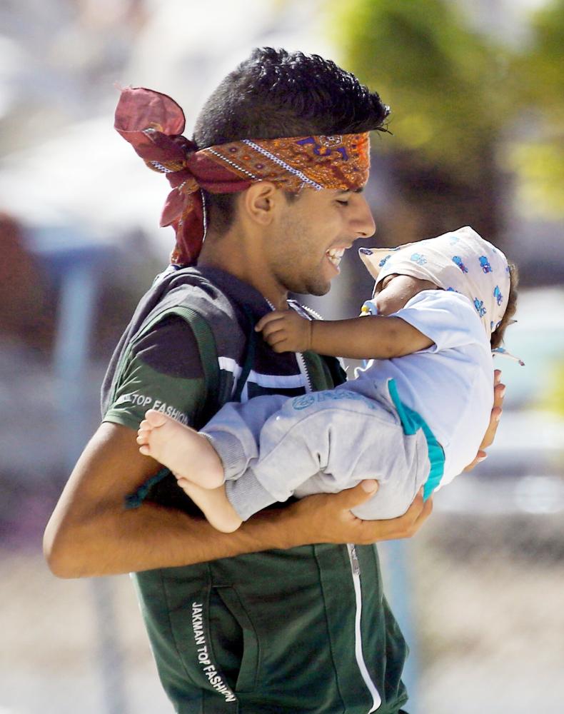 



سوري فار من الرقة يحمل طفله في مخيم عين عيسى للنازحين أمس الأول. (أ ف ب)