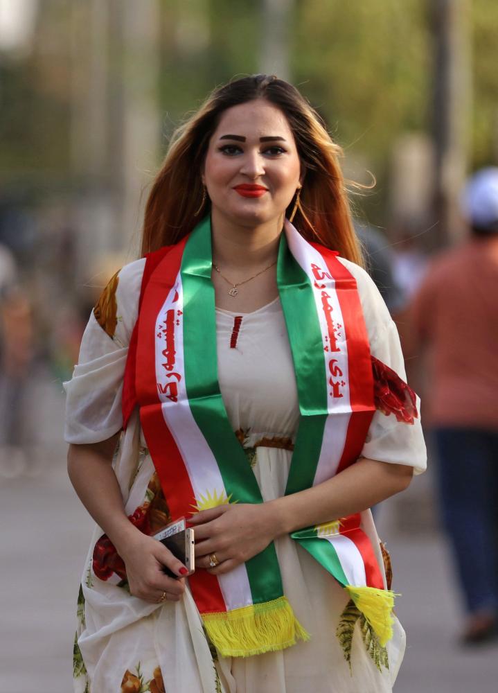 An Iraqi Kurdish woman draped in a scarf bearing the colours of the Kurdish flag arrives to cast her vote in the referendum on independence at a polling station in Arbil, the capital of the autonomous Kurdish region of northern Iraq, on September 25, 2017. The non-binding vote, initiated by veteran Kurdish leader Massud Barzani, has angered not only Baghdad, following which Iraq's federal parliament demanded that troops be sent to disputed areas in the north controlled by the Kurds since 2003, but also neighbours Turkey and Iran who are concerned it could stoke separatist aspirations among their own sizeable Kurdish minorities. / AFP / SAFIN HAMED
