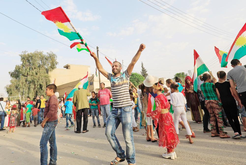 Syrian Kurds dance with the Kurdish flag as they celebrate in the northeastern Syrian city of Qamishli on September 25, 2017, in support of the independence referendum in Iraq's autonomous northern Kurdish region. Iraqi Kurds voted in an independence referendum, defying warnings from Baghdad and their neighbours in a historic step towards a national dream. / AFP / Delil souleiman
