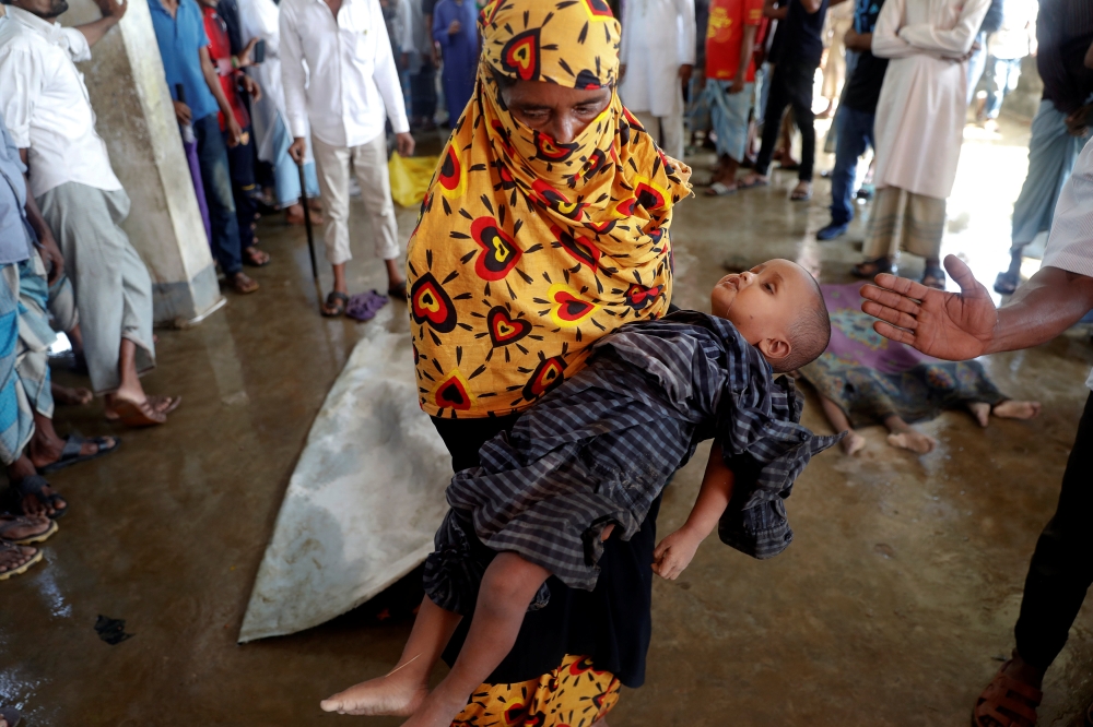 The body of one of the Rohingya refugee children who died after their boat capsized, as they were fleeing Myanmar, is prepared for the funeral just behind Inani Beach near Cox's Bazar, Bangladesh September 29, 2017. REUTERS/Damir Sagolj TEMPLATE OUT