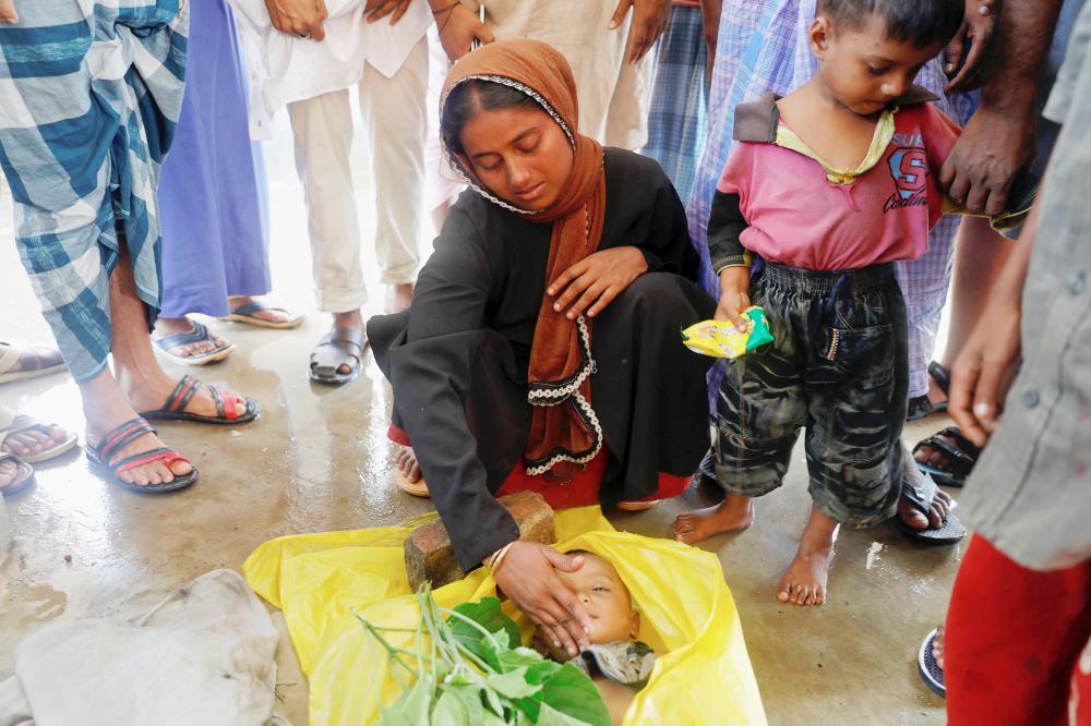 ATTENTION EDITORS - VISUAL COVERAGE OF SCENES OF DEATH Nur Fatema, a survivor, touches the face of her nine-month old son, who died after a boat with Rohingya refugees capsized as they were fleeing Myanmar, before bodies of victims were taken for the mass funeral just behind Inani Beach near Cox's Bazar, Bangladesh September 29, 2017. REUTERS/Damir Sagolj TEMPLATE OUT