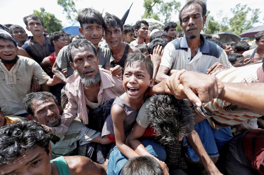 FILE PHOTO: A boy is pulled to safety as Rohingya refugees scuffle while queueing for aid at Cox's Bazar, Bangladesh, September 26, 2017. REUTERS/Cathal McNaughton/File Photo