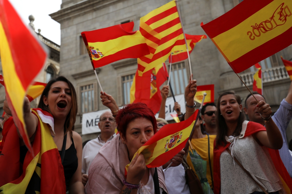 A woman kisses a Spanish flag as protesters hold Spanish and Catalan flags during a demonstration in favor of a unified Spain a day before the banned October 1 independence referendum, in Barcelona, Spain, September 30, 2017. REUTERS/Susana Vera