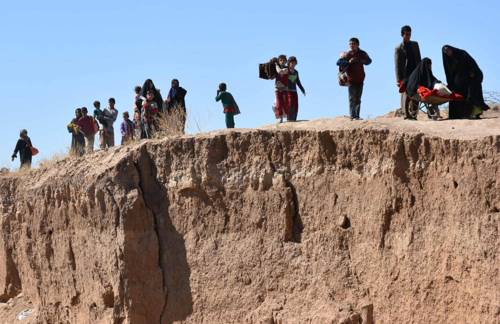 TOPSHOT - Displaced Iraqis who fled from the ongoing battles to oust the Islamic State (IS) group from Hawija, walk a long the bank of a river in the area of Zarga some 35 kilometres southeast of Kirkuk on October 4, 2017.   Iraqi forces pushed into the Islamic State group stronghold of Hawija commanders said, stepping up their assault against one of the jihadists' last enclaves in the country.

 / AFP / Marwan IBRAHIM
