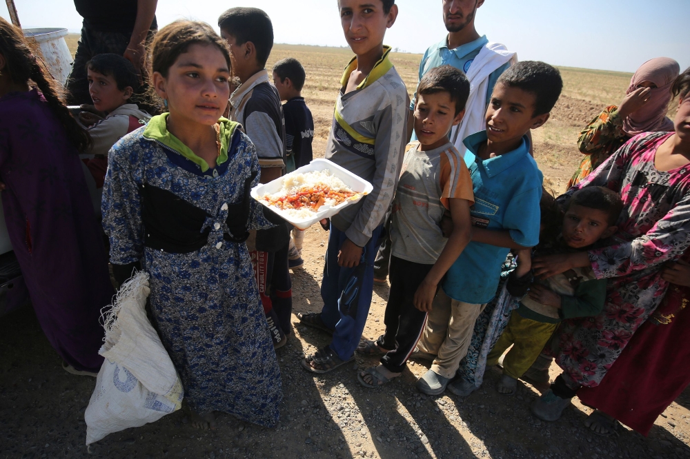 Iraqi children receive food from a charity in a village on the outskirts of Hawija on October 6, 2017, a day after Iraqi forces retook the northern city from Islamic State (IS) group fighters. / AFP / AHMAD AL-RUBAYE 