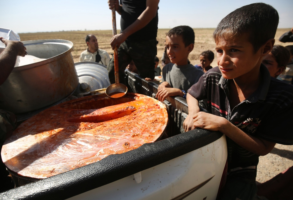 Iraqi children receive food from a charity in a village on the outskirts of Hawija on October 6, 2017, a day after Iraqi forces retook the northern city from Islamic State (IS) group fighters. / AFP / AHMAD AL-RUBAYE 