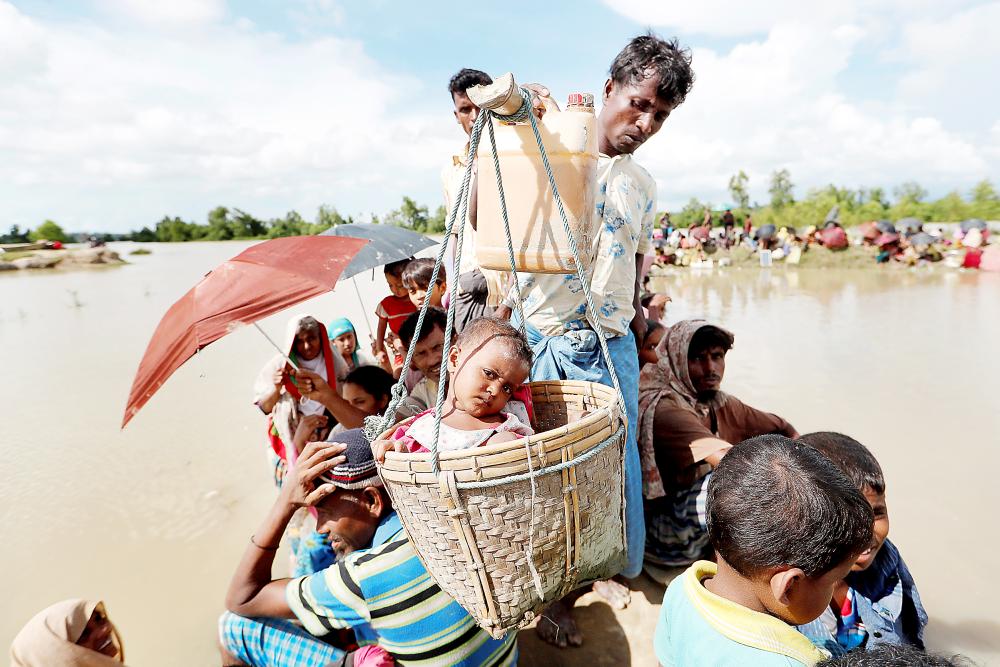 روهينغيون يعانون مأساة الفرار خلال اجتيازهم قنوات مائية وحقول أرز أمس الأول. (رويترز)