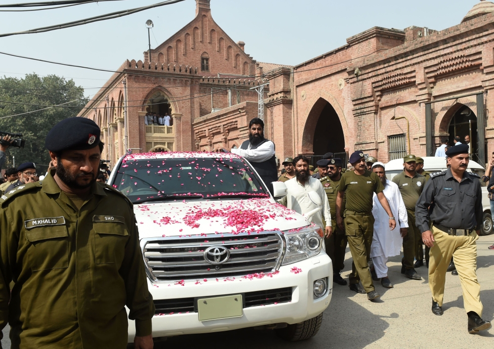 Pakistani policemen escort a vehicle carrying the head of of the Jamaat-ud-Dawa (JuD) organisation Hafiz Saeed as he leaves the court after the expiry of his three-month detention period, in Lahore on October 17, 2017. Saeed, designated a global terrorist by the US and who has a $10 million bounty on his head was placed under house arrest by the Pakistani authorities on January 31, 2017. / AFP / ARIF ALI
