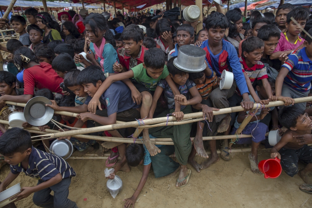 Rohingya Muslim children, who crossed over from Myanmar into Bangladesh, jump over a bamboo fence to break the queue as they wait to receive food handouts distributed to children and women by a Turkish aid agency at Thaingkhali refugee camp, Bangladesh, Saturday, Oct. 21, 2017. UNICEF says the children who make up most of the nearly 600,000 Rohingya Muslims who have fled violence in Myanmar are seeing a «hell on earth» in overcrowded, muddy and squalid refugee camps in neighboring Bangladesh. Children account for 58 percent of the refugees who have poured into Cox's Bazar, Bangladesh, over the last eight weeks. (AP Photo/Dar Yasin)