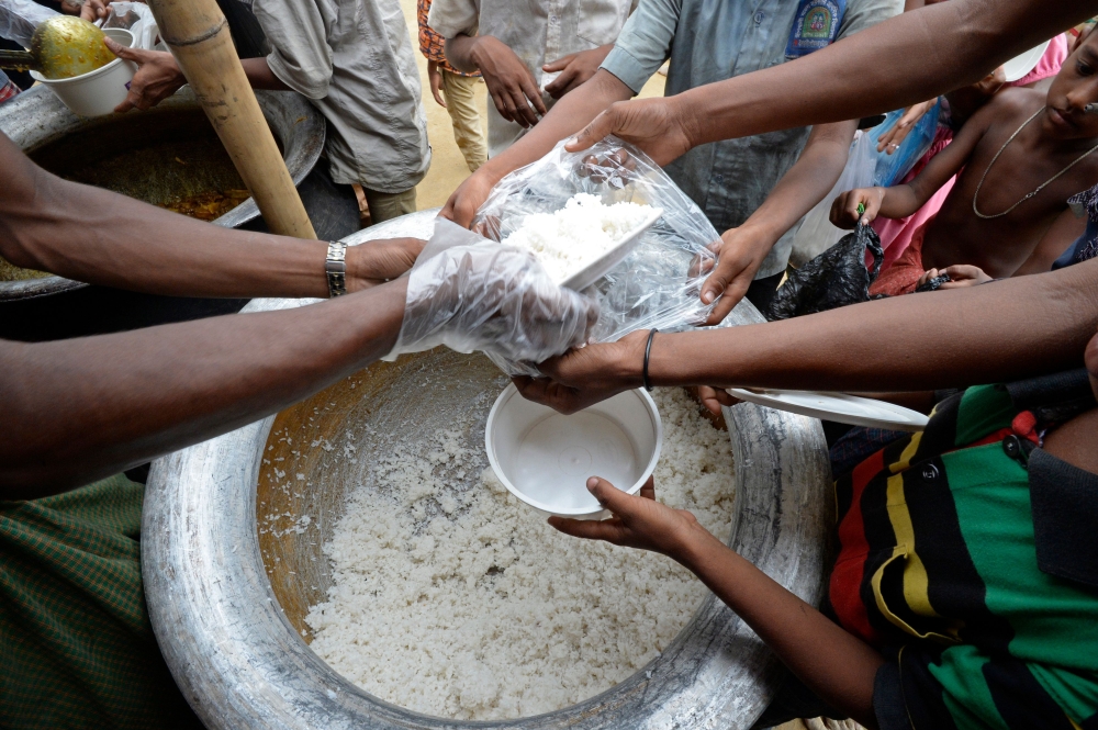 Rohingya Muslim refugees receive food distributed by a Turkish aid agency at Thaingkhali refugee camp in Ukhia on October 21, 2017. Thousands of Rohingya Muslims stranded near Bangladesh's border this week after fleeing violence in Myanmar have finally been permitted to enter refugee camps after «strict screening», officials said on Ocotber 19. / AFP / TAUSEEF MUSTAFA 