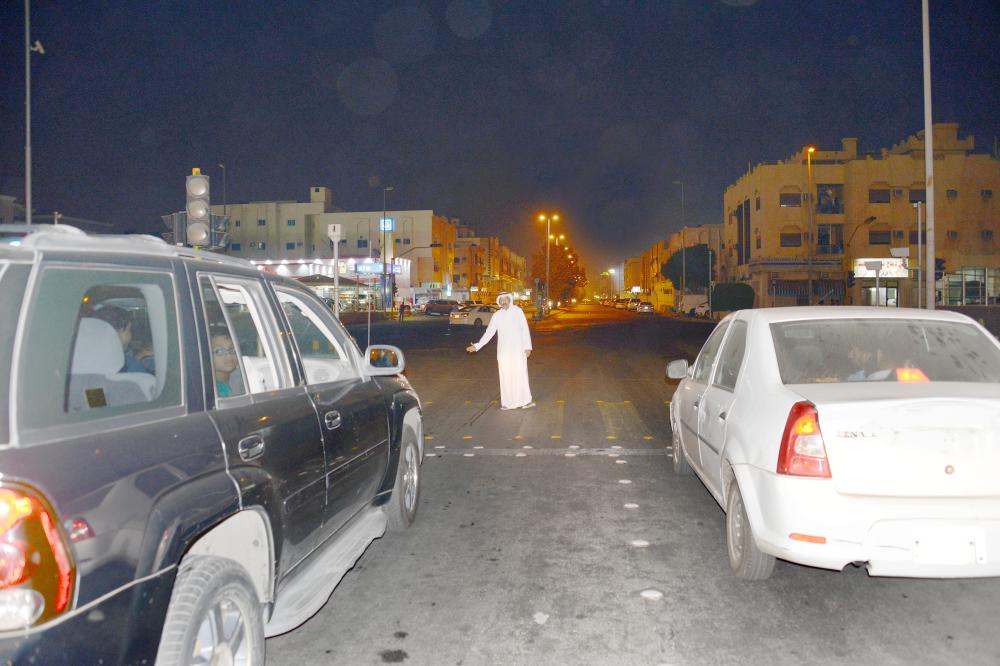 عدد من أبناء الحي ينظمون الحركة المرورية في ظل غياب رجال المرور. (تصوير عبدالسلام السلمي)