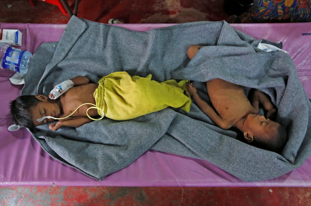 Ruaida Begum (L), 3, suffering from severe malnutrition, and her brother Nurul Amin, 1, suffering from pneumonia, lie on a bed at a diarrhoea treatment centre in Kutupalong refugee camp near Cox's Bazar, Bangladesh October 28, 2017. REUTERS/Adnan Abidi