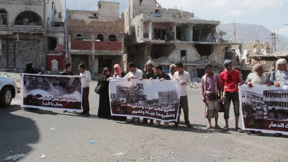 ناشطون يمنيون ينظمون فعاليات احتجاجية أمام مباني دمرتها الميليشيات الانقلابية فوق رؤوس المدنيين في تعز.(عكاظ).(
