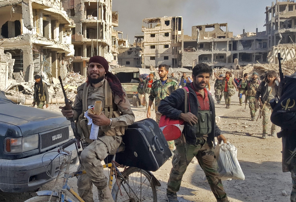 Syrian soldiers, and pro-government forces, are seen in front of damaged buildings in the eastern Syrian city of Deir Ezzor on November 3, 2017. The Islamic State jihadist group lost control of two of the last major towns under its grip in Syria and Iraq, as Syrian troops and Iraqi security forces advanced in the Euphrates Valley border region.
Syrian forces entered Deir Ezzor city in September, breaking an IS siege of nearly three years on government-held parts of the provincial capital. / AFP / STRINGER
