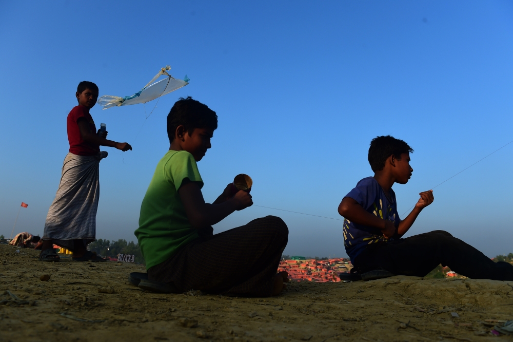 Rohingya Muslim refugees fly kites in Tangkhali refugee camp in the Bangladeshi district of Ukhia on November 25, 2017. An estimated 618,000 Muslim Rohingya have fled mainly Buddhist Myanmar since a military crackdown was launched in Rakhine in August triggered an exodus, straining resources in the impoverished country. / AFP / Munir UZ ZAMAN
