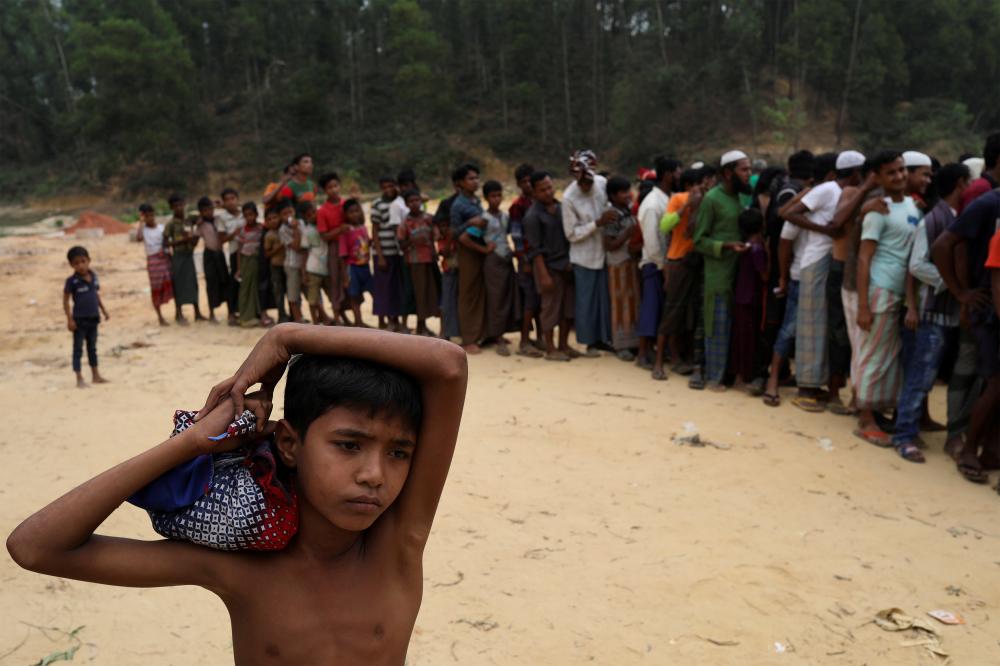 



روهينغية تحمل رضيعها بانتظار الحصول على بطانيات في مخيم للاجئين في بنغلاديش أمس الأول. (رويترز)