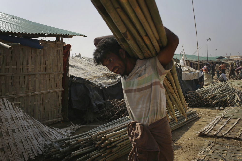 A Rohingya Muslim man carries bamboo used to construct tents in Kutupalong refugee camp on Saturday, Nov. 25, 2017, in Bangladesh. The United Nations and others have said the military's actions appeared to be a campaign of 