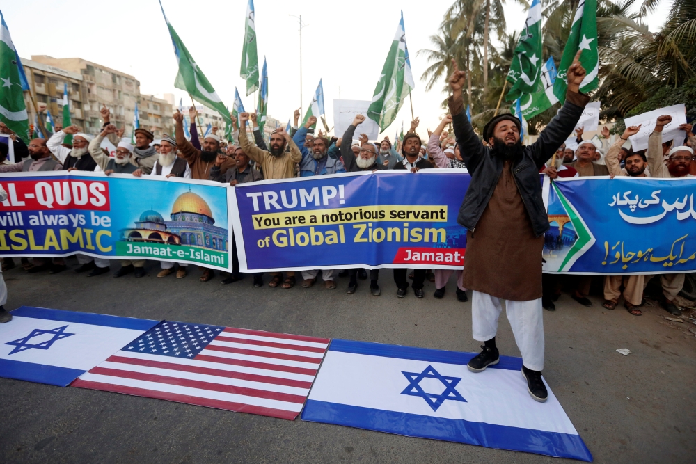 A supporter of religious and political party Jamaat-e-Islami (JI) chants slogans with others as he stands on Israeli flag during a protest against U.S. President Donald Trump's decision to recognize Jerusalem as the capital of Israel, in Karachi, Pakistan December 7, 2017. REUTERS/Akhtar Soomro