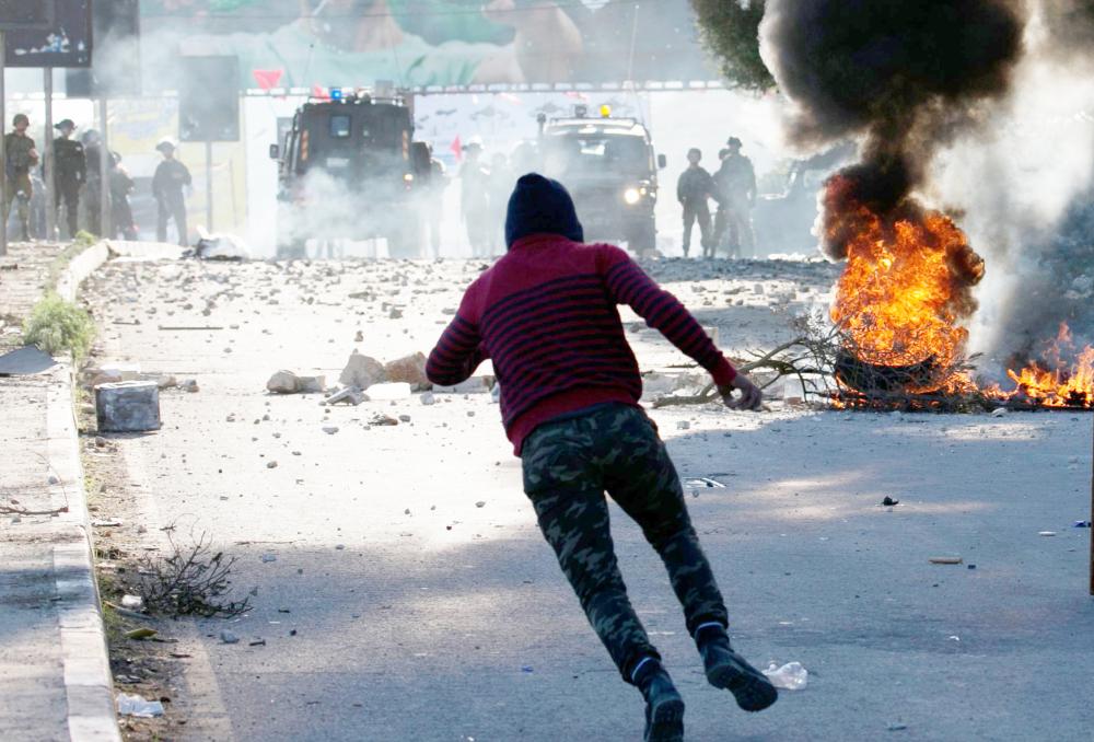 Palestinian protestors throw stones towards Israeli security forces at Hawara checkpoint, south of the West Bank city of Nablus, during clashes following a demonstration against US President Donald Trump's decision to recognise Jerusalem as the capital of Israel on December 8, 2017.  Palestinians clashed with Israeli security forces after calls for a 