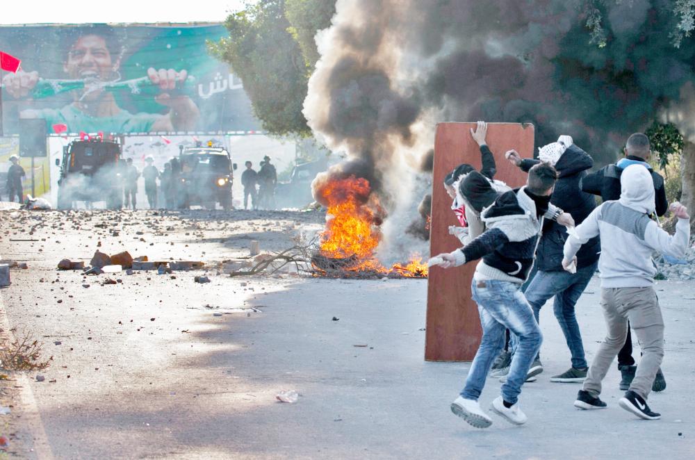 Palestinian protestors throw stones towards Israeli security forces at Hawara checkpoint, south of the West Bank city of Nablus, during clashes following a demonstration against US President Donald Trump's decision to recognise Jerusalem as the capital of Israel on December 8, 2017.  Palestinians clashed with Israeli security forces after calls for a 