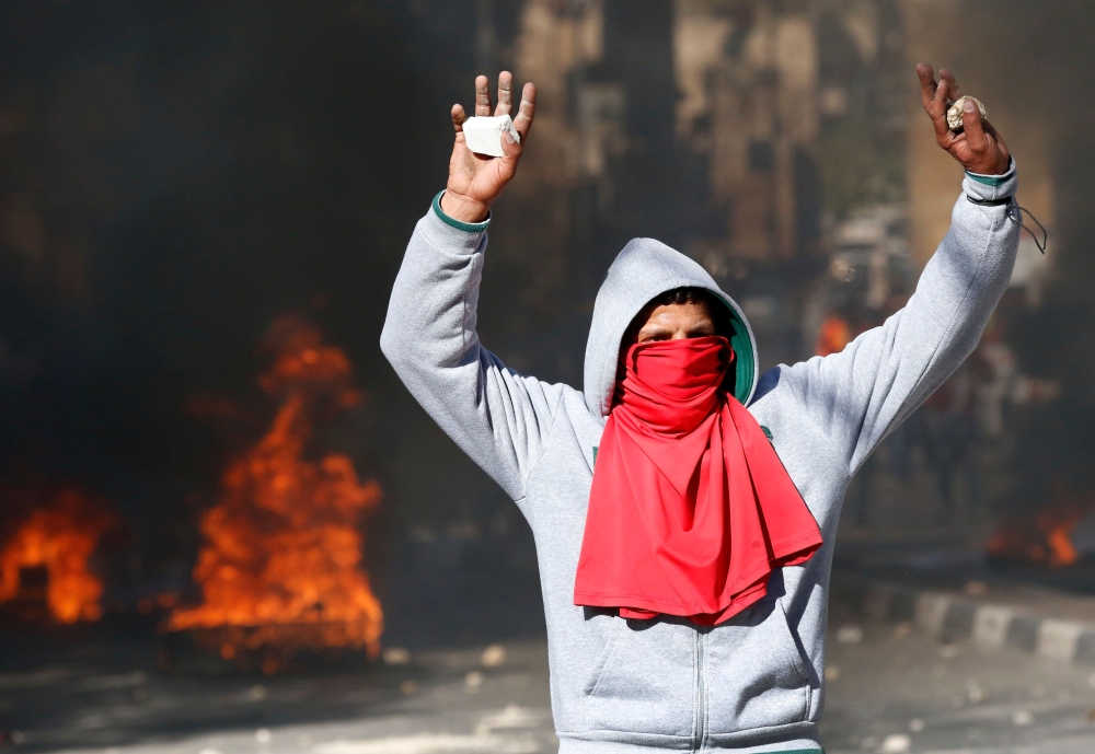 A Palestinian protestor holds up stones during clashes with Israeli security forces after the weekly Friday prayers in the city centre of the West Bank town of Hebron on December 8, 2017. Palestinians clashed with Israeli security forces after calls for a 