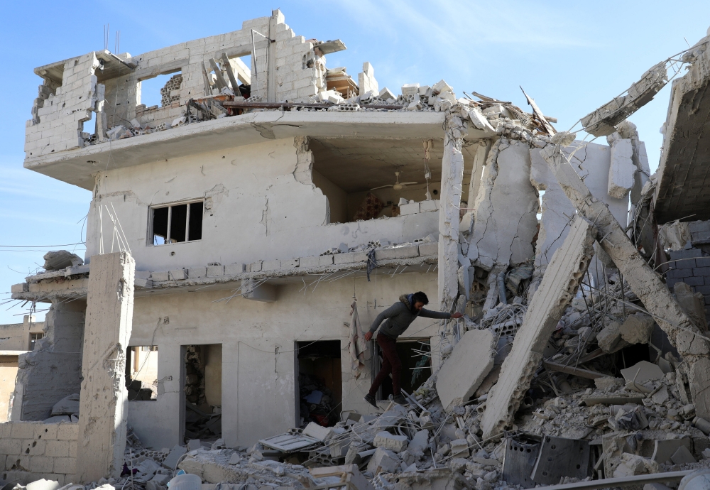 A man is seen on the rubble of damaged buildings in the rebel-held area, in the city of Deraa, Syria December 12, 2017. REUTERS/Alaa al-Faqir