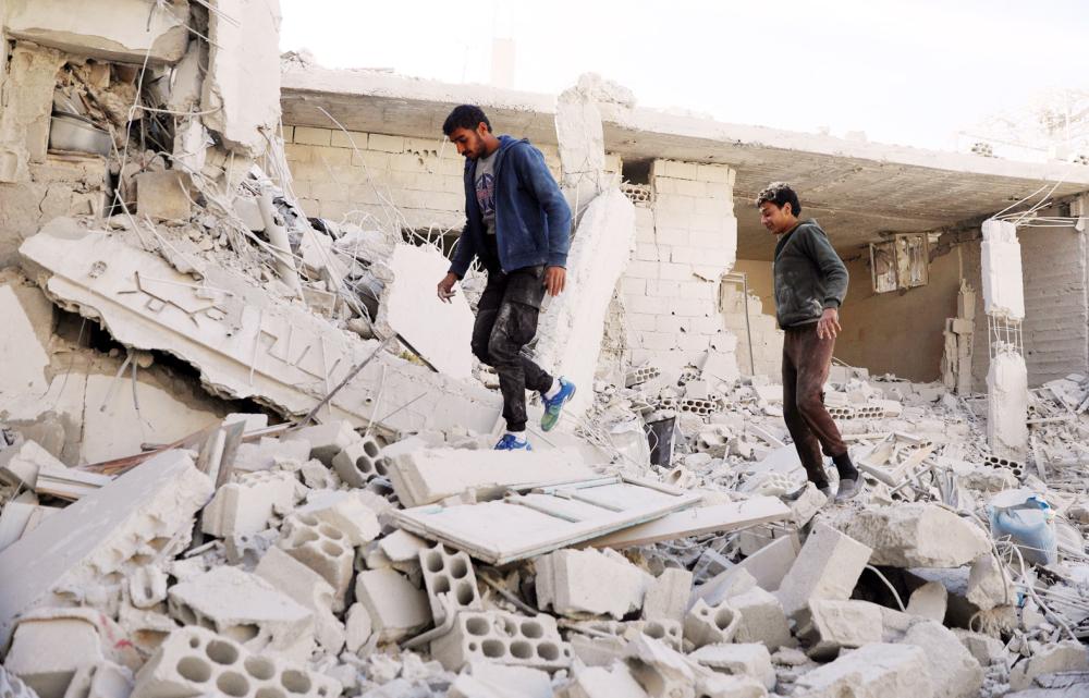 Men walk on rubble of damaged buildings in the rebel-held area, in the city of Deraa, Syria December 12, 2017. REUTERS/Alaa al-Faqir