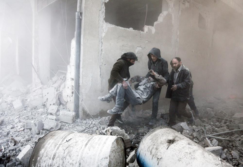 



أفراد من الدفاع المدني يحملون جريحا أصيب في غارة جوية لنظام الأسد على عربين في الغوطة أمس الأول. (أ ف ب)