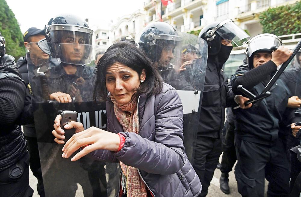  تونسية في حالة هلع من الشرطة خلال مظاهرة ضد الغلاء في العاصمة أمس. (أ ف ب) 