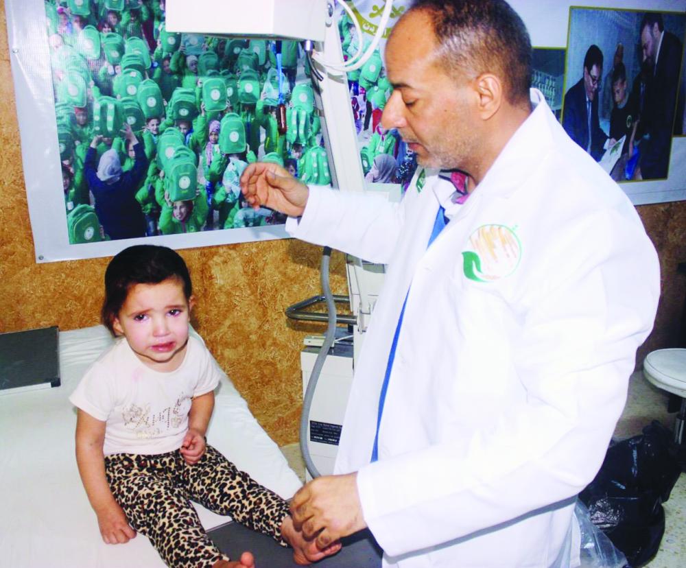 



طبيب يفحص طفلاً سورياً في عيادات مركز الملك سلمان أمس. (واس)