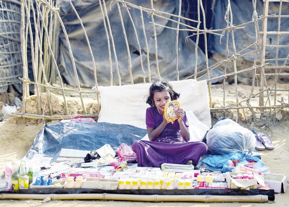 



طفلة روهينغية تشاهد وجهها في مرآة في مخيم للاجئين في بنغلاديش أمس الأول. (أ.ف.ب)