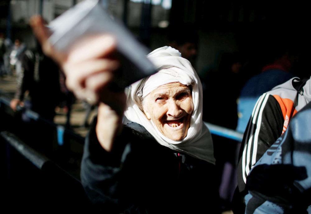 مسنة فلسطينية تلوح بأوراقها الثبوتية أثناء تلقيها معونات غذائية في مركز تابع للأمم المتحدة في غزة أمس الأول. (رويترز)