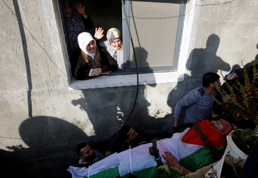 فلسطينية تلوح بيدها أثناء تشييع جثمان شاب في الضفة الغربية أمس. (رويترز)