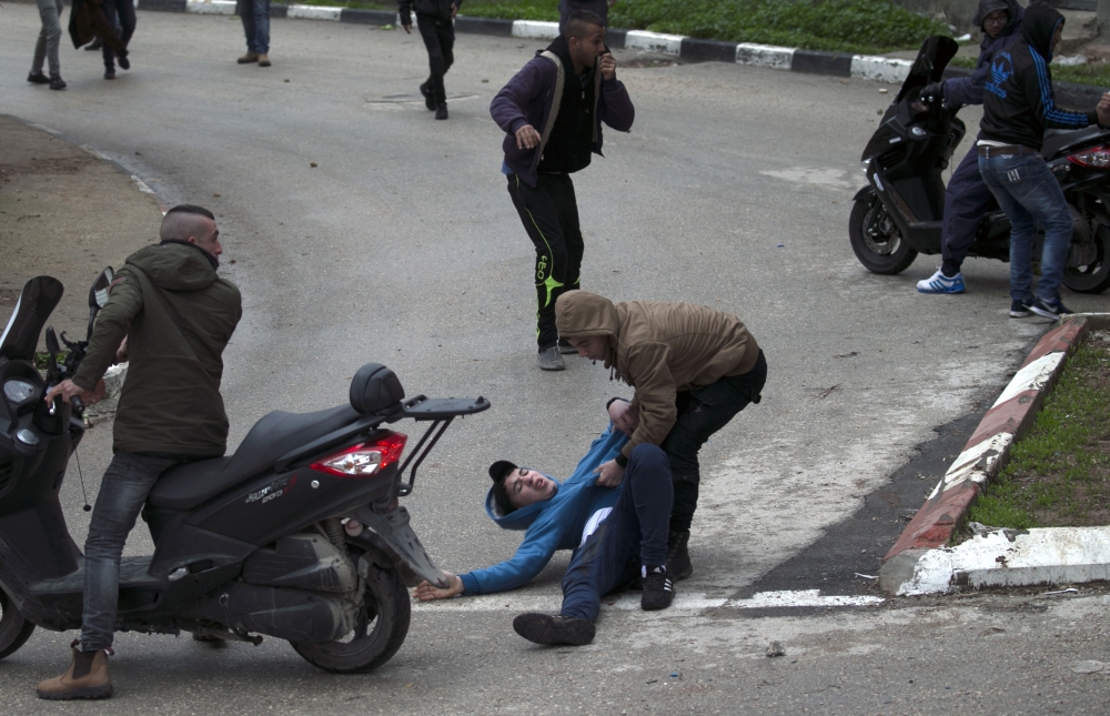 Palestinian youths evacuate a wounded comrade during clashes with Israeli forces in Jenin, in the north of the occupied West Bank, on January 18, 2018.  A Palestinian was killed during clashes with Israeli forces in Jenin, the Palestinian health ministry announced. Israel's Shin Beth security services said shots were fired during a raid by border guards to capture the alleged perpetrators of an attack earlier this month in which a rabbi was shot dead.
 / AFP / JAAFAR ASHTIYEH
