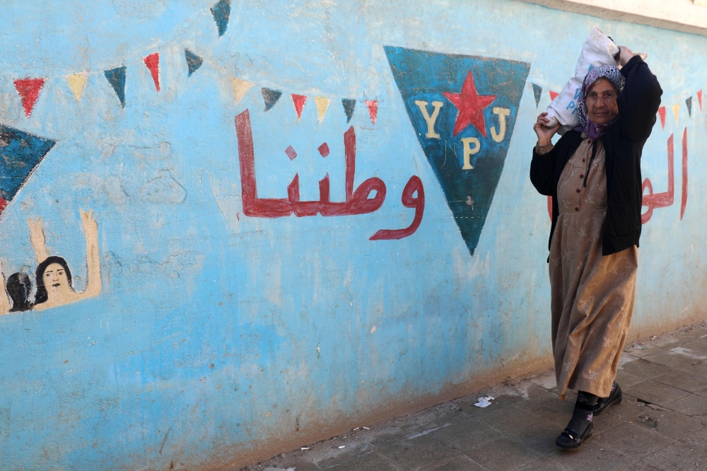 A Syrian Kurdish woman walks in a street in the Kurdish enclave of Afrin on January 30, 2018. Turkey launched operation «Olive Branch» on January 20 against the Syrian Kurdish People's Protection Units (YPG) militia in Afrin, supporting Syrian opposition fighters with ground troops and air strikes. / AFP / DELIL SOULEIMAN
