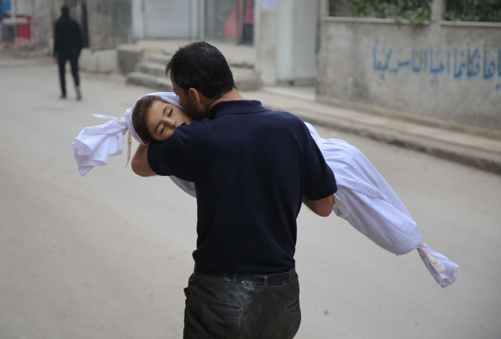 EDITORS NOTE: Graphic content / A man kisses the body of his child ahead of his funeral in Zamalka, near Syria's capital Damascus on February 5, 2018, following reported airstrike.  / AFP / Amer ALMOHIBANY
