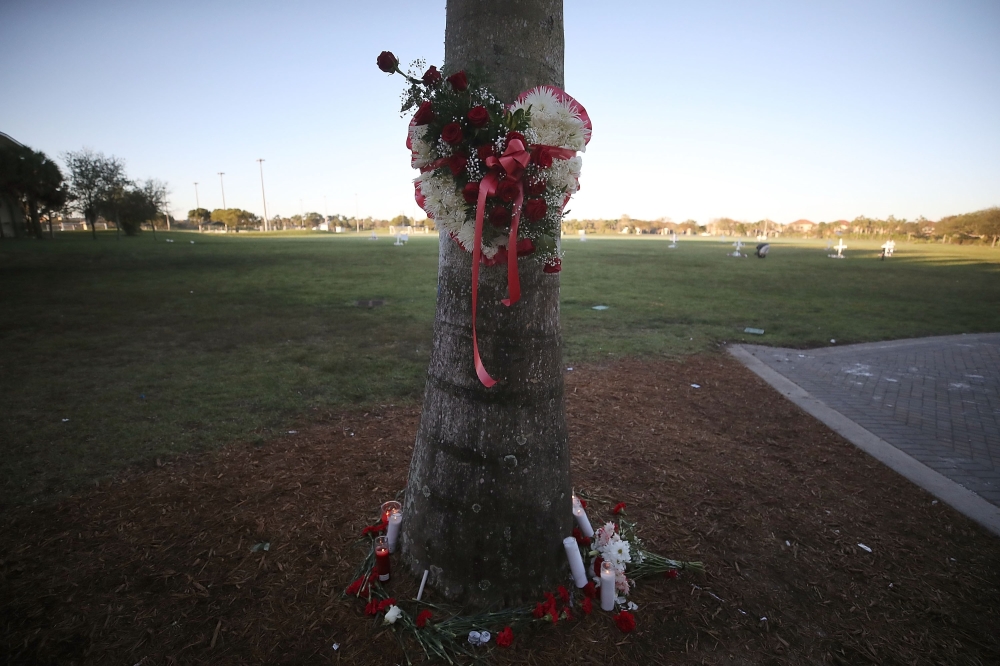 PARKLAND, FL - FEBRUARY 16: Flowers and candles are placed around a palm tree to honor victims of the mass shooting at Marjory Stoneman Douglas High School, at Pine Trail Park on February 16, 2018 in Parkland, Florida. Police arrested 19 year old former student Nikolas Cruz for killing 17 people at the high school.   Mark Wilson/Getty Images/AFP
== FOR NEWSPAPERS, INTERNET, TELCOS & TELEVISION USE ONLY ==
